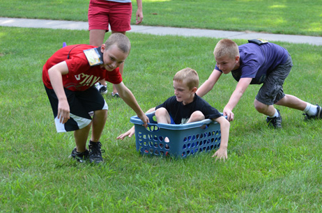 Two Boys Pulling & Pushing Another Boy in Laundry Basket
