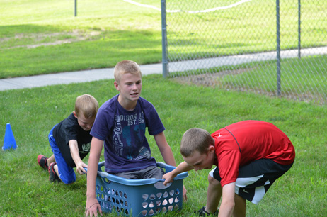 Two Boys Pulling & Pushing Another Boy in Laundry Basket