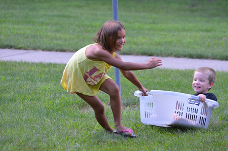 Girl Pulling Small Boy in Laundry Basket