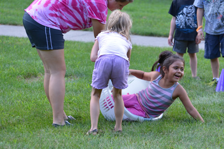 Girl in Laundry Basket Tipping Over with Girl Trying to Pull Basket