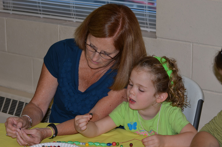 Rita Helping Girl Make Necklace