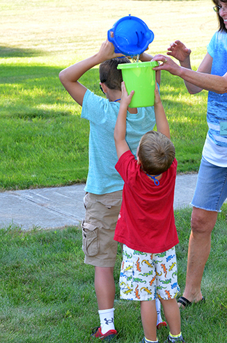 Child Passing Bucket of Water