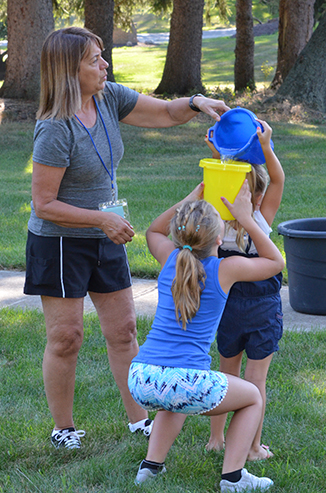 Child Passing Bucket of Water