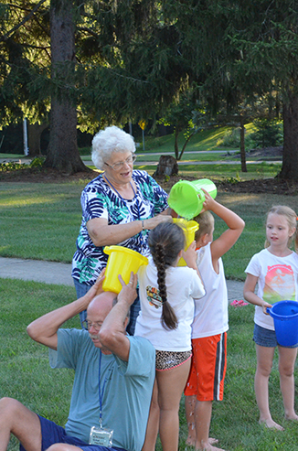 Child Passing Bucket of Water