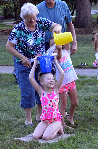 Child Passing Bucket of Water