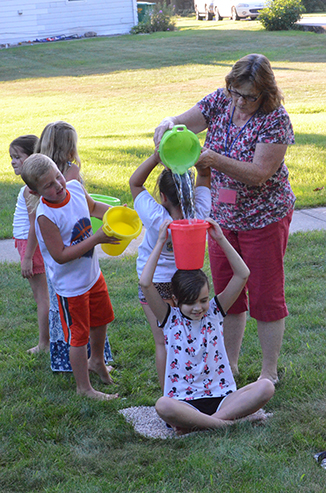 Child Passing Bucket of Water